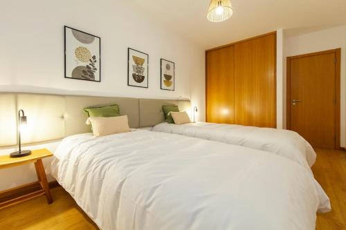 a large white bed in a room with a table at Sea waves - Olhão in Olhão