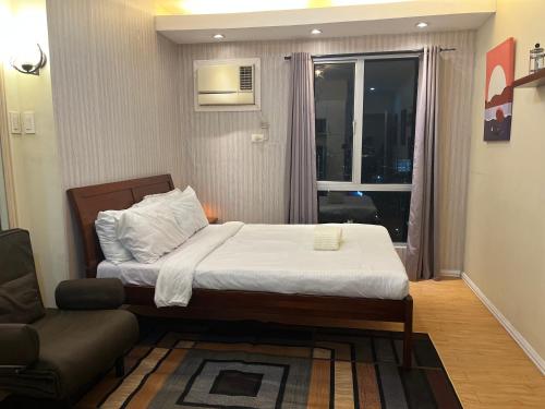 a bedroom with a bed and a couch and a window at Studio unit inside IT Park Wifi & Netflix in Cebu City