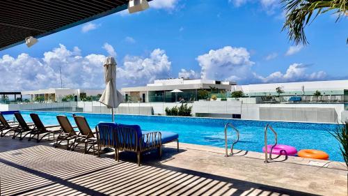 a swimming pool with chairs and an umbrella at Ipana Luxury Suites By Caribe Rentas in Playa del Carmen
