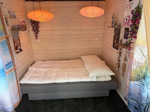 a bed in a corner of a room with two lights at Happy Mermaid Garden Cabin in Aalborg