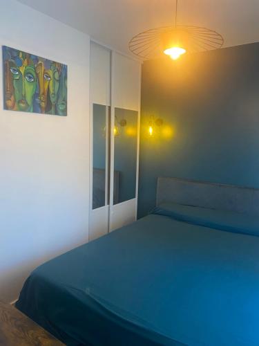 une chambre avec un lit bleu et un miroir dans l'établissement APP RDC GRANDE TERRASSE 43 m2 air-conditioned apartment MAX 6 PEOPLE, à Vallauris