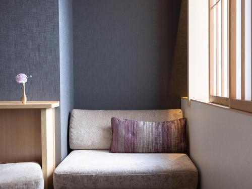 a couch with a purple pillow in a room at Mitsui Garden Hotel Kyoto Shinmachi Bettei in Kyoto