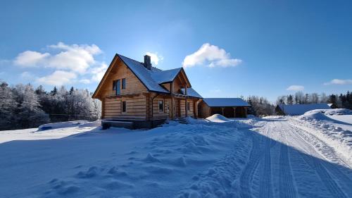 a log cabin in the snow with footprints in the snow at Drewniana chata in Cisówek