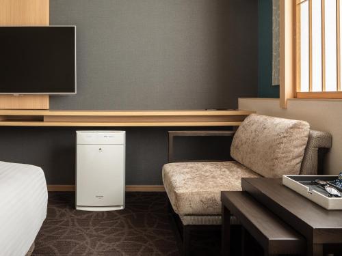 a room with a bed and a chair and a tv at Mitsui Garden Hotel Kyoto Shinmachi Bettei in Kyoto