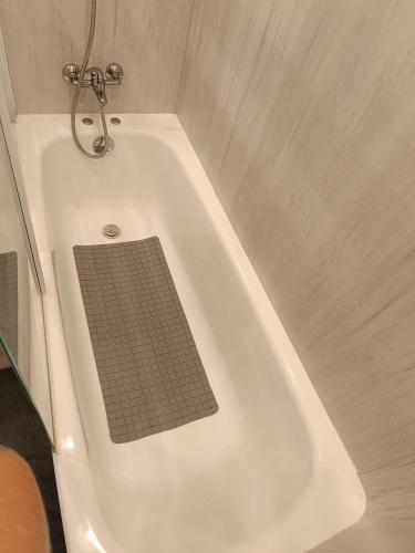 La salle de bains est pourvue d'une baignoire blanche avec un lavabo. dans l'établissement Charmant appartement au bord de mer, à Fouesnant