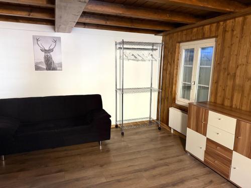 a living room with a black couch and a window at Appartment Happy Life - Wimmis - near Spiez-Thun- Interlaken in Arni Alp