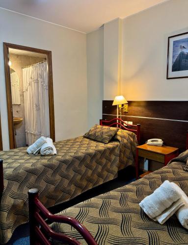a hotel room with two beds and a table at Nuevo Hotel Pacifico in Mendoza
