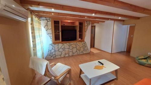 a living room with a table and a stone wall at Family apartment in old town in Cres