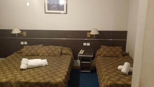 a room with two beds and a desk with a phone at Nuevo Hotel Pacifico in Mendoza
