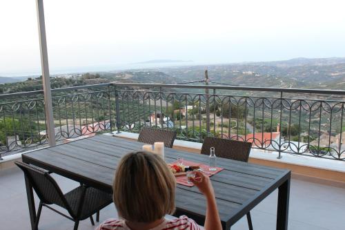 a woman sitting at a table on a balcony at Myron Luxury Living in Agios Myronas