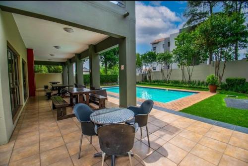 een terras met een tafel en stoelen en een zwembad bij Eden Place in Vosburg