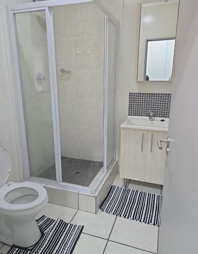 a bathroom with a shower and a toilet and a sink at Eden Place in Johannesburg