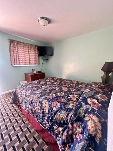 a bedroom with a bed with a comforter on it at Your Motel in Ypsilanti