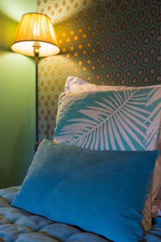 a bed with a blue pillow next to a lamp at Le Jardin d'Emile in Cassis