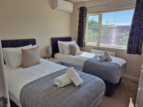 a bedroom with two beds with towels on them at Air Conditioned 3-Bed Home with Garden & Parking in Willen