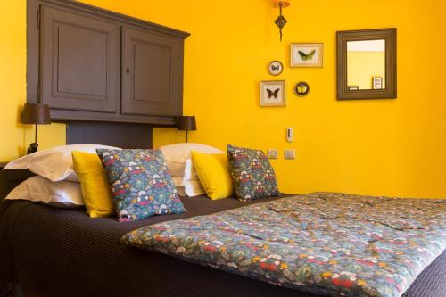 a bedroom with yellow walls and a bed with colorful pillows at Le Jardin d'Emile in Cassis
