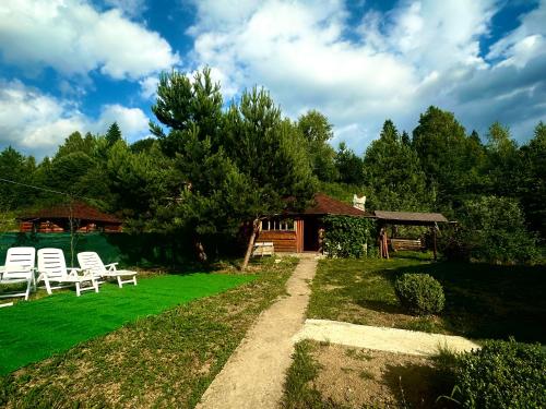 a garden with two white chairs and a cabin at Подих Карпат in Slavske
