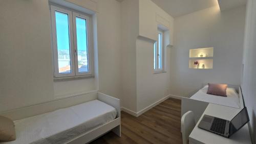 a white room with a bed and a laptop on a desk at De Angelis Apartments - GOLD in Sant'Agnello
