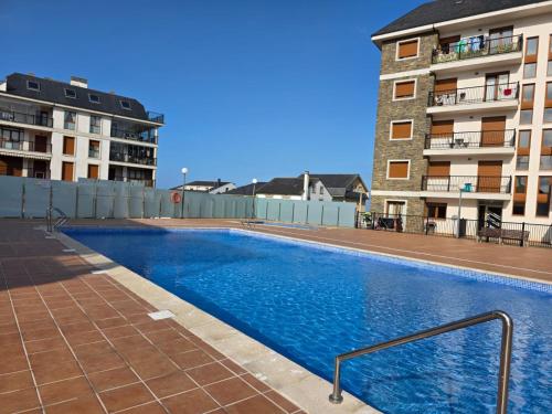 a large swimming pool in front of a building at Costa Foz Apartment Playa de Llas, terraza, piscina y pista de pádel in Foz