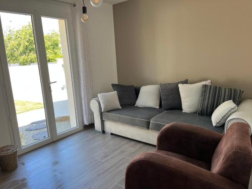 ein Wohnzimmer mit einer Couch und einer Glasschiebetür in der Unterkunft chambre d'hotes Les 3 moineaux in Aigrefeuille-dʼAunis