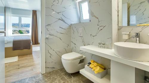 ein Badezimmer mit einer weißen Toilette und einem Waschbecken in der Unterkunft Vila Bernarda by Resort Čulina in Metajna