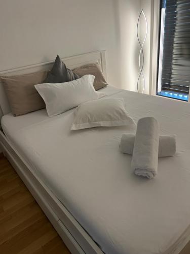 Una cama blanca con almohadas y una toalla. en Coqueto, en Ginebra