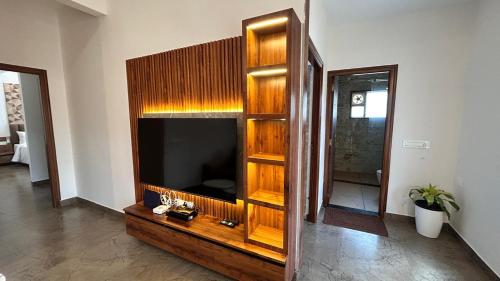 a living room with a entertainment center with a flat screen tv at Tranquil Touch in Chikmagalūr