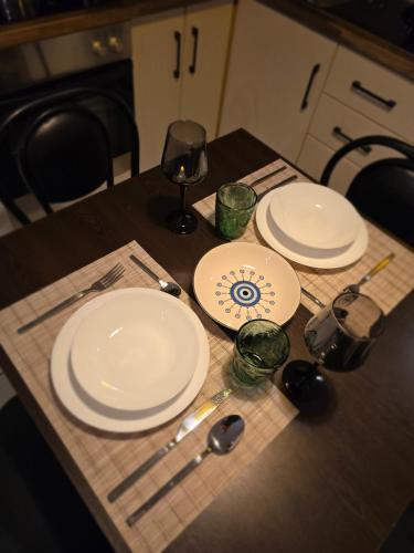 a table with two white plates and a glass of wine at Feel like home 1 in Shkodër