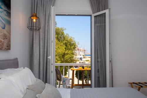 a bedroom with a bed and a balcony with a view at Mykonos Windmills View in Megali Ammos