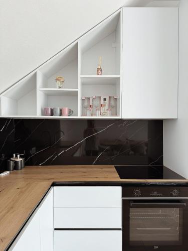 a kitchen with white cabinets and black appliances at Peaceful Place Near Lake in Sankt Pölten