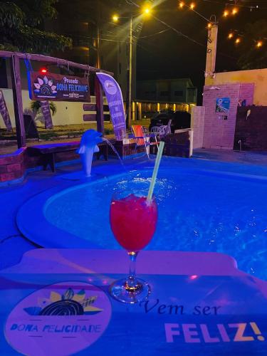 a drink sitting on a table next to a swimming pool at Pousada Dona Felicidade Carneiros in Tamandaré