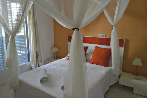 Apartamentos de las Heras في مدينة إيبيزا: غرفة نوم بسرير أبيض مع مظلة