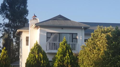 a white house with trees in front of it at Mountain View Guest House in Underberg in Underberg