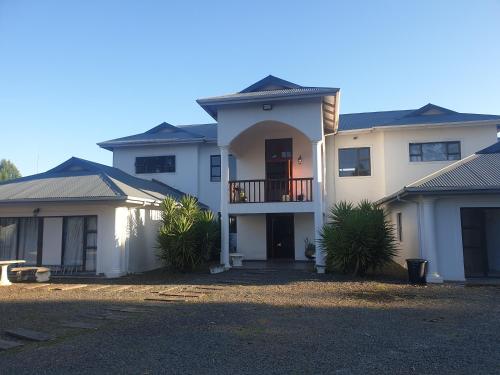 a large white house with a balcony on top at Mountain View Guest House in Underberg in Underberg
