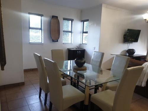 a dining room with a glass table and white chairs at Mountain View Guest House in Underberg in Underberg