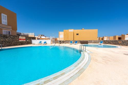 Una gran piscina con sillas y un edificio. en El Poris, en Porís de Abona