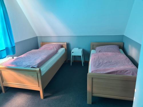 two twin beds in a room with a table at Monteurzimmer Jusy - HK in Varel