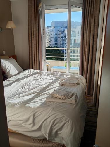 - un lit avec serviettes dans une chambre avec fenêtre dans l'établissement ApparthotelParisDefenseArenaElyseeEiffel, à Courbevoie