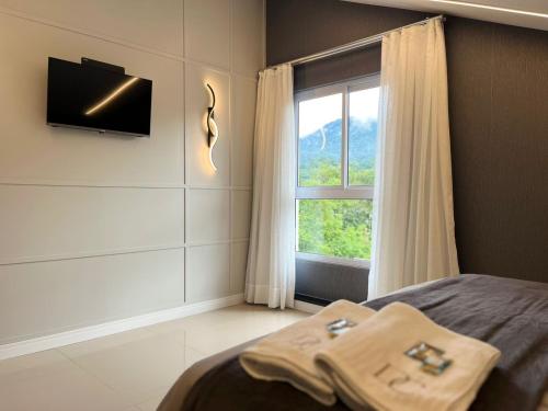 a bedroom with a bed with a television and a window at Loft Dona Clara 201 Centro de Pomerode in Pomerode