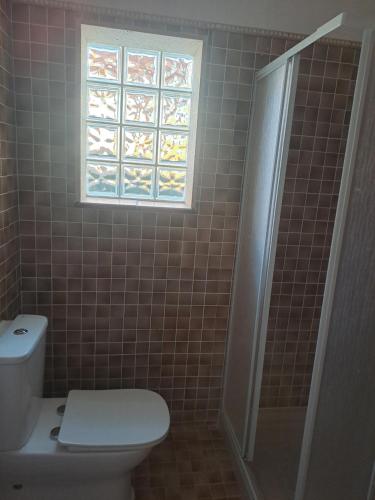 a bathroom with a toilet and a window at Triana y mar in Roda de Bará
