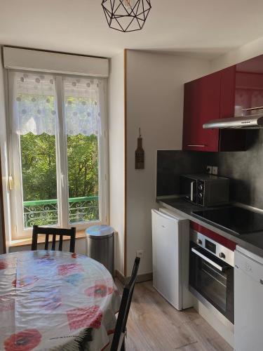 une cuisine avec une table et une cuisine avec des placards rouges dans l'établissement Appartement T2 Les Capucines avec balcon, à Le Mont-Dore