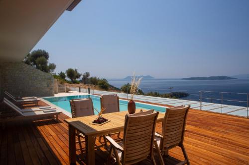 a wooden deck with a table and chairs and a pool at 2S Villas Resort - Cave Villas in Sivota