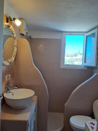 a bathroom with a sink and a toilet and a window at Spacious apartment with view and garden for kids! in Tinos Town