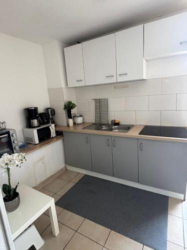 eine Küche mit weißen Schränken und einem Tisch in der Unterkunft Chambre à 20 minutes de Paris NOTRE DAME, APPARTEMENT COMMUN in Épinay-sur-Seine