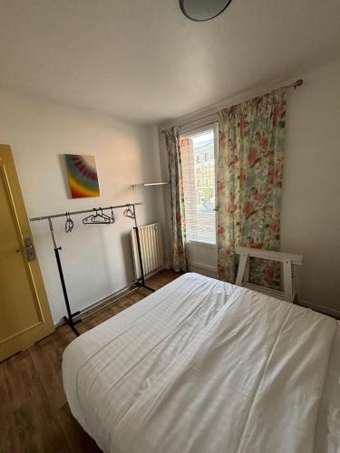 ein Schlafzimmer mit einem weißen Bett und einem Fenster in der Unterkunft Chambre à 20 minutes de Paris NOTRE DAME, APPARTEMENT COMMUN in Épinay-sur-Seine