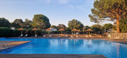 une piscine avec chaises et parasols dans un complexe hôtelier dans l'établissement Eden Cala Rossa appartement 3 chambres et grande terrasse dans résidence hotelière Fiori di Cala Rossa à Lecci, à Lecci