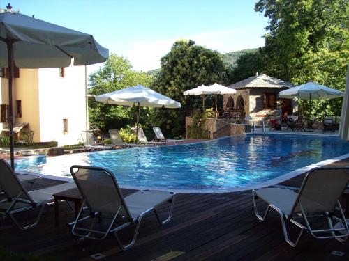 a large blue swimming pool with chairs and umbrellas at Amalthia Traditional Guesthouse in Tsagarada