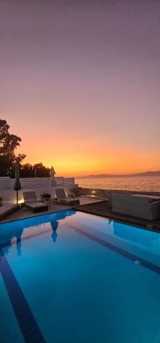 a swimming pool with a sunset over the ocean at Vaso Beach Front Villa in Ialyssos