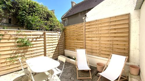 two chairs and a table in front of a fence at La perle-Maison de pêcheur à Saint-Aubin-sur-Mer in Saint-Aubin-sur-Mer