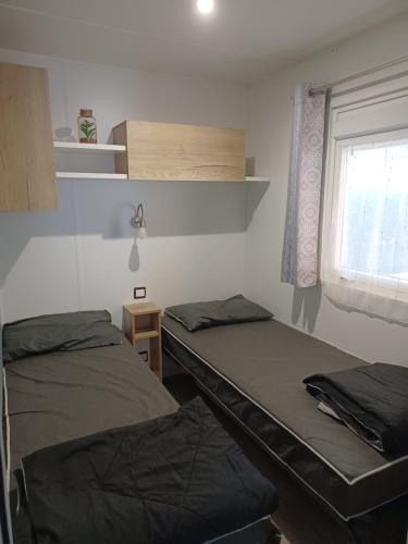 deux lits dans une chambre avec une fenêtre dans l'établissement Mobil Home 710 Bora Bora 3 chambres, à Gastes